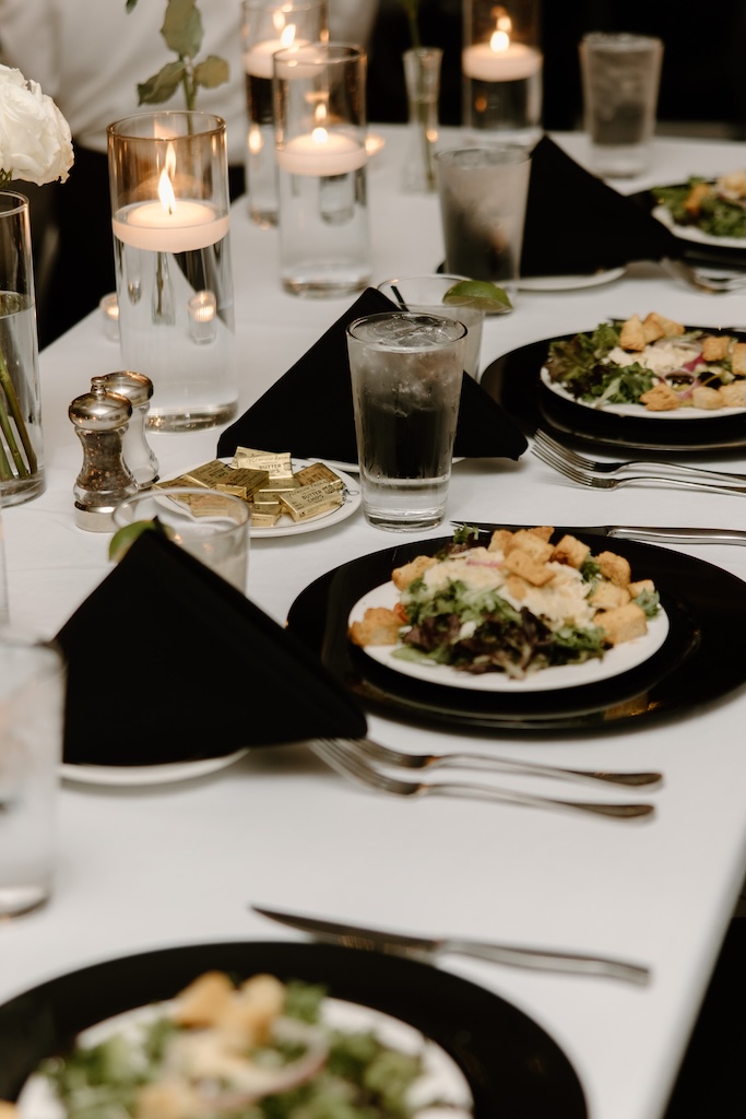 wedding table set up with plates of food, utensils, and candles